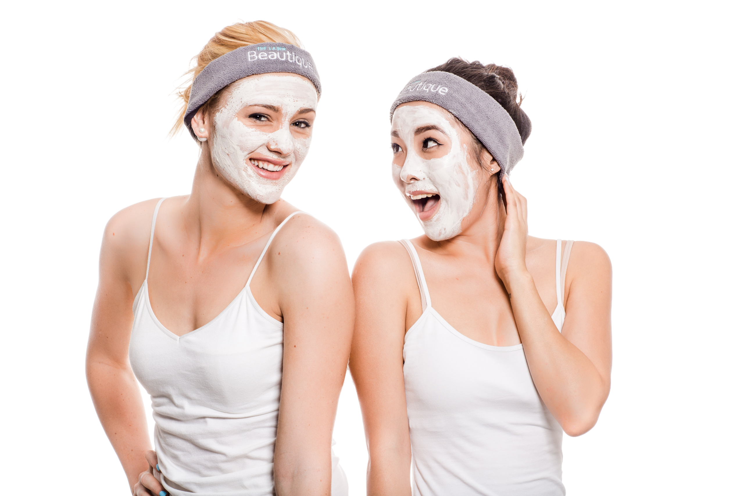 Two women with skincare facial masks on and wearing The Laser Beautique headbands on their heads